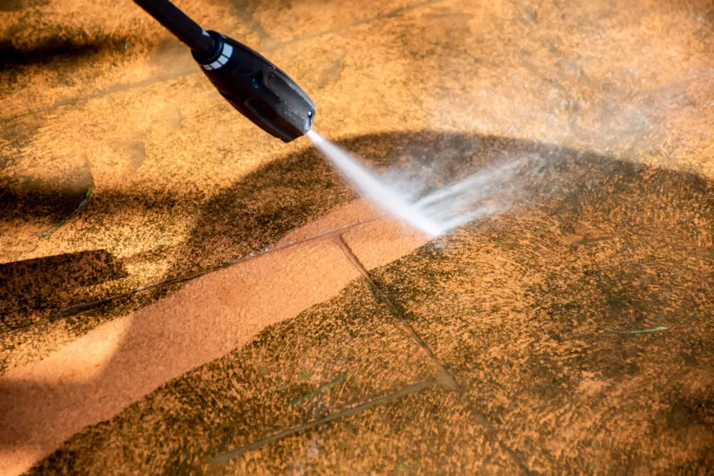 Cleaning backyard paving tiles pathway with high pressure washer. Spring clean up.