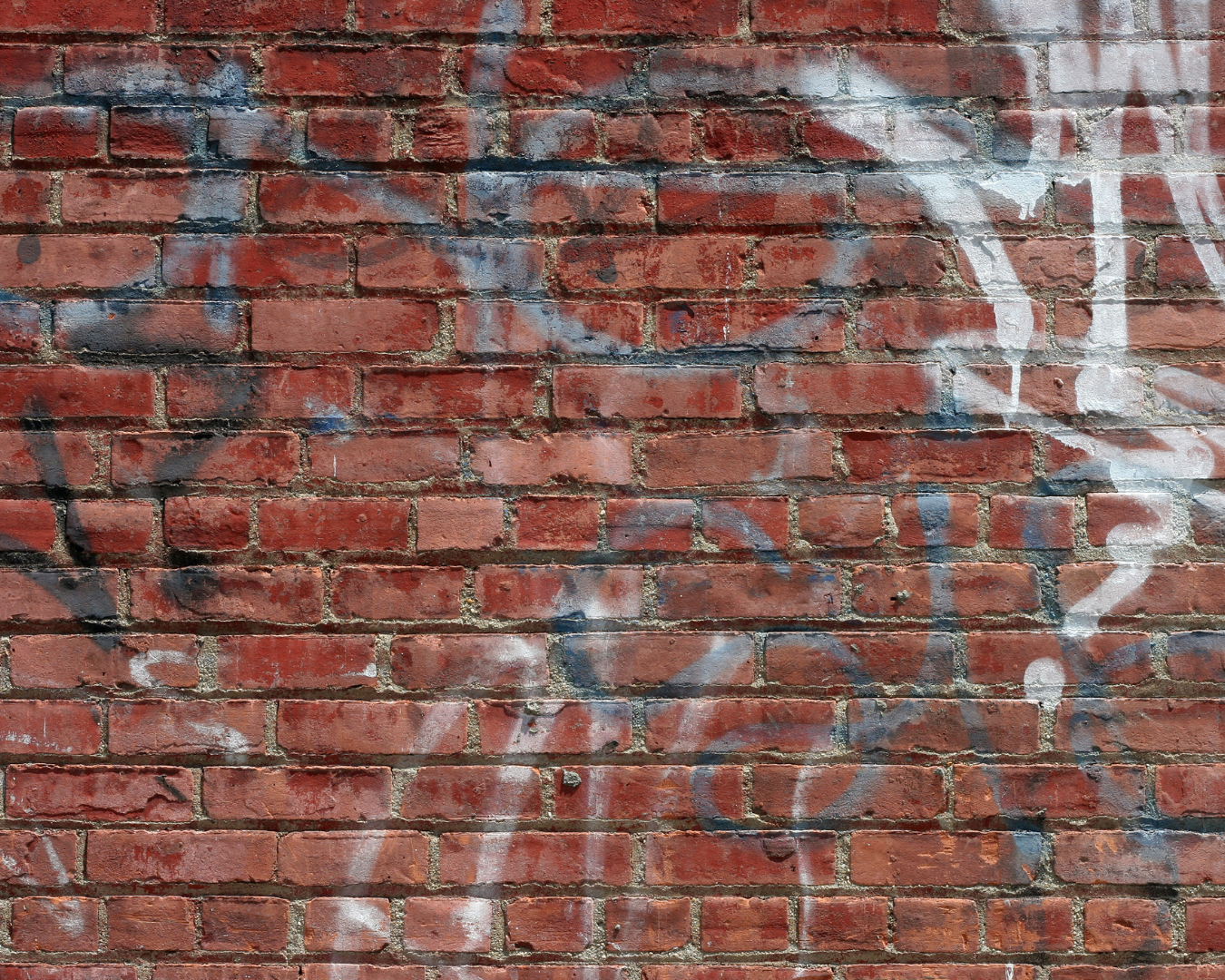 Close-up shot of brick wall covered in graffiti.
